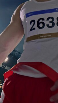 Male runner breaking finish line tape in victory celebration at night stadium