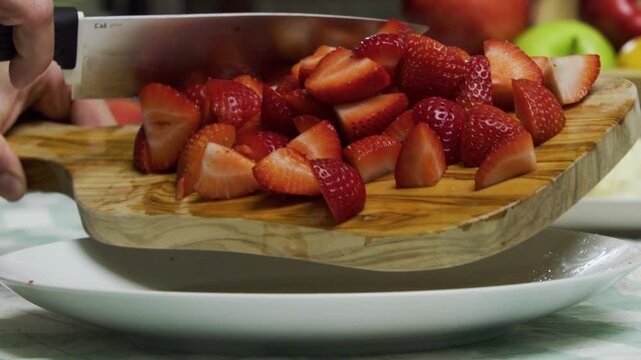 Diced strawberries being dropped onto plate - closeup, slow motion shot