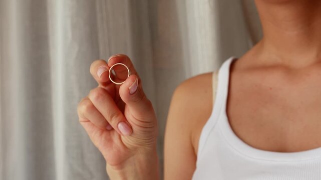 Woman holding wedding ring, broken heart after betrayal, divorce, breakup and painful process of letting go