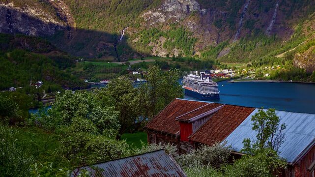 View of the scenic village of Flam nestled along the fjord with traditional wooden houses, lush green mountains, and calm blue waters in Flam, Vestland, Norway.