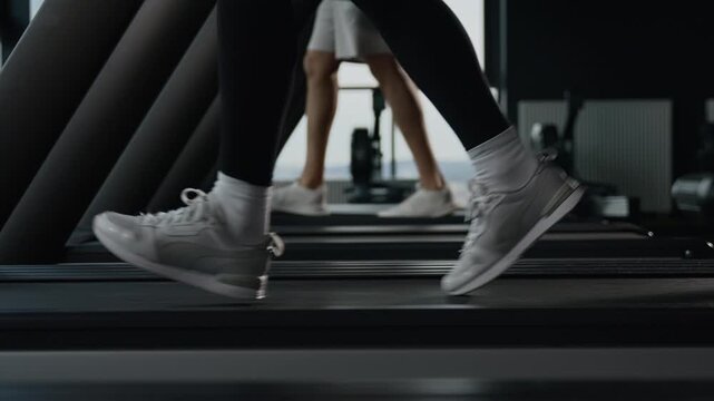 Close up female legs run on treadmill inside fitness gym sports shoes moving on running machine unknown girl sportswoman cardio workout jogging active runner feet step speed training healthy lifestyle