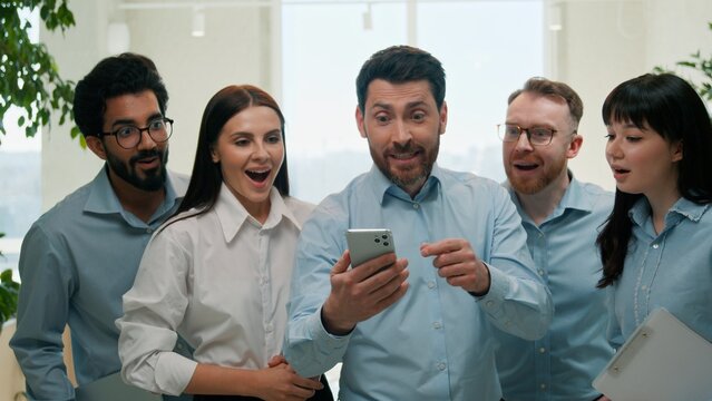 Successful multiethnic business team celebrating achievement mobile phone indoor office happy businessmen businesswomen smartphone rejoice colleagues online victory finance triumph excitement teamwork