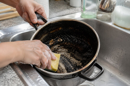 Cleaning Burnt Pot with Sponge After Cooking Accident in Kitchen