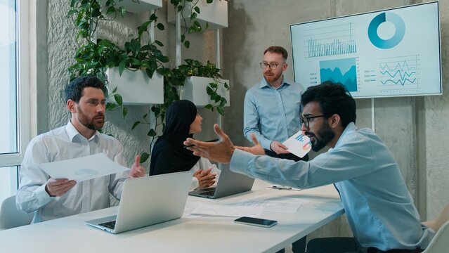 Diverse multiethnic business team men muslim businesswoman in hijab discussing ideas office briefing table analyzing strategy interactive board brainstorm colleagues meeting teamwork planning indoors