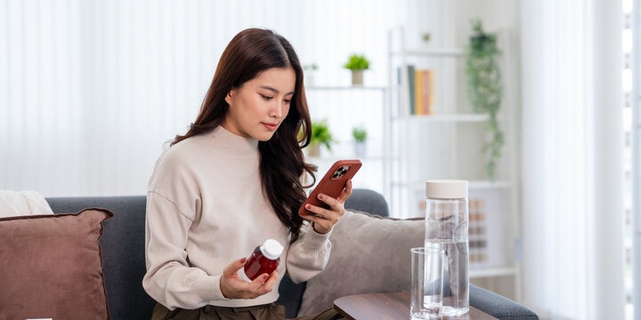 A woman is holding a bottle of medicine and using her smartphone to search online for medication instructions.