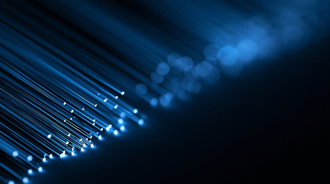 Glowing blue fiber optic cables on dark background. High-speed internet and global data transmission concept.