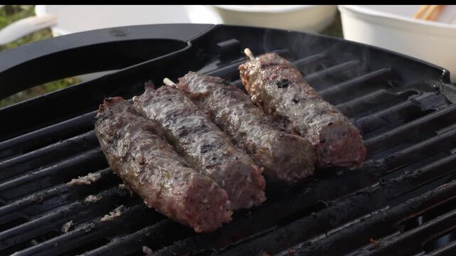 Minced beef or lamb kebabs grill, sear and smoke over hot charcoal outdoors in real time, barbecue cuisine, summer cookout