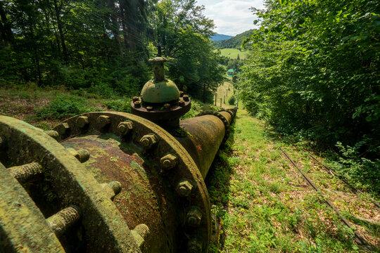 View of the historic penstock and valve of the Jasenie Hydroelectric Power Plant running through a lush forest in Jasenie, Banska Bystrica Regio, Slovakia.