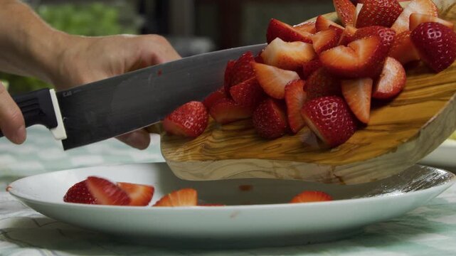Slow motion shot of diced strawberries dropping onto plate