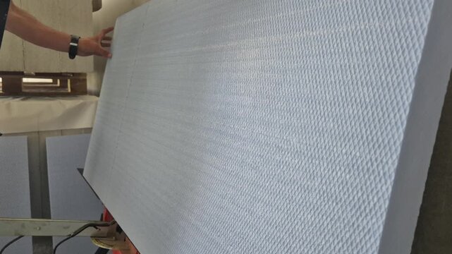 Side view profile shot of a worker cutting through an extruded polystyrene (XPS) foam board from the end with a hot wire cutter.