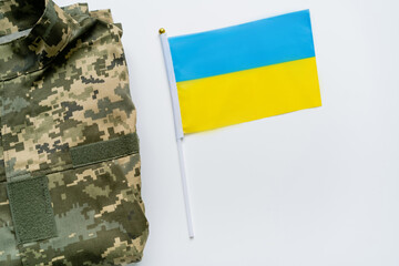Fototapeta premium A camouflage uniform rests beside a small flag of Ukraine, symbolizing pride and resilience.