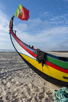 Traditional Arte Xavega fishing boat on an Ovar beach with a Portuguese flag