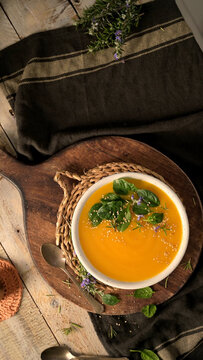 Creamy pumpkin soup served in a white bowl with spinach leaves and sesame seeds