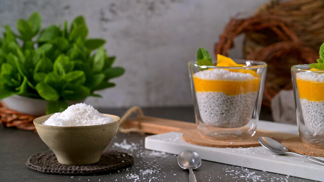 Chia seed pudding with mango puree and coconut flakes served in glass cups