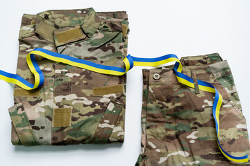 Obraz premium Camouflaged military uniform shown with a blue and yellow ribbon of national pride.