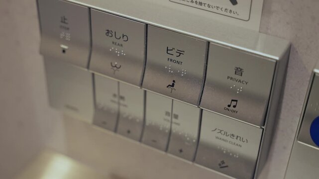 Modern Japanese toilet control panel with various buttons for bidet functions, privacy sounds, and cleaning, featuring both Japanese and English text along with braille for accessibility