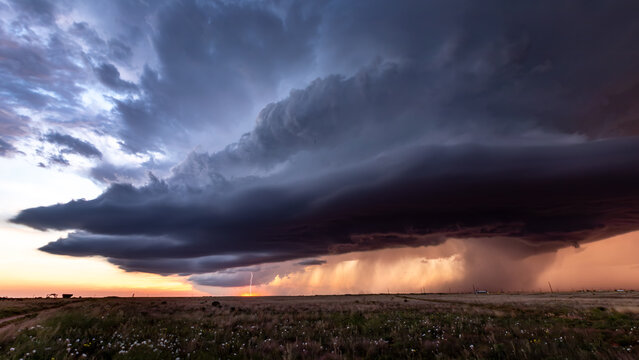 View of a dramatic supercell thunderstorm with a lightning strike over a vast prairie landscape during sunset in Oklahoma City, Oklahoma, United States.
