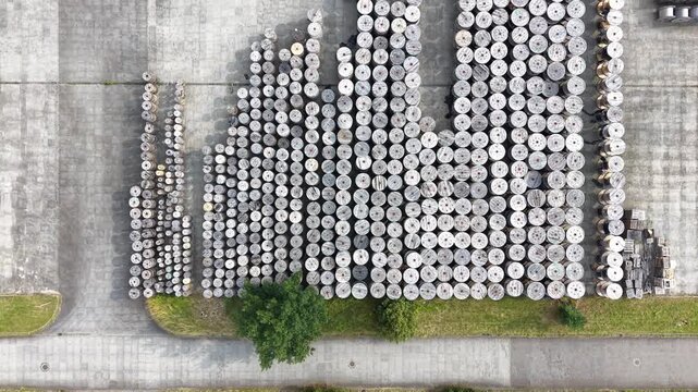 Aerial view of a warehouse displaying a large arrangement of wooden cable reels organized in rows, showcasing a systematic layout across the expansive concrete surface. Industrial place