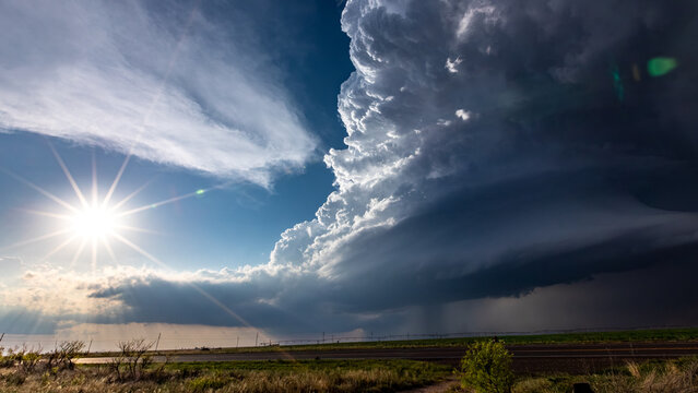 View of a dramatic supercell storm cloud with a bright sunburst over the flat landscape of Oklahoma City, Oklahoma, United States.