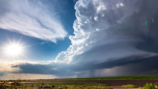 View of a massive supercell storm cloud with dramatic lighting and dark rain curtains over a rural landscape in Oklahoma City, Oklahoma, United States.