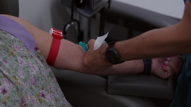 Close up of a healthcare worker performing a venipuncture procedure on a female patient in a clinical setting. Authentic medical care and diagnostic testing.