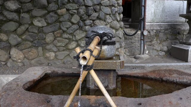A temizuya (purification water basin) where worshippers ritually cleanse their hands and mouth before entering Fushimi Inari Shrine, Kyoto, Japan.