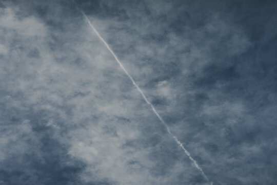 Laane County, Estonia - 02 June 2024: View of a contrail cutting across a cloudy blue sky over Vormsi.