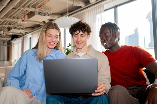 Friends Collaborate on Business Project Using Laptop in Office