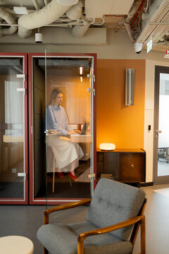 Woman working on laptop in office booth