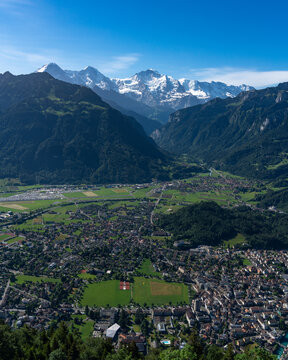 View of the town of Unterseen nestled in the valley below the snow-capped peaks of the Bernese Alps as seen from Harder Kulm, Unterseen, Canton of Bern, Switzerland.
