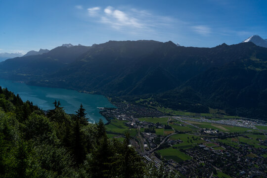View of Harder Kulm overlooking the town of Unterseen, the turquoise waters of Lake Thun, and the dramatic Bernese Alps under a clear blue sky in Unterseen, Canton of Bern, Switzerland.