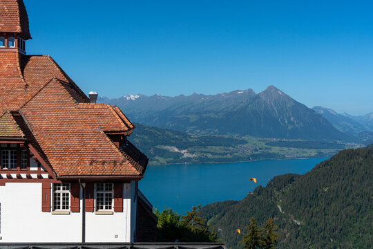 View of the Harder Kulm restaurant with its red-tiled roof, overlooking the turquoise waters of Lake Brienz and the Bernese Alps in Unterseen, Canton of Bern, Switzerland.