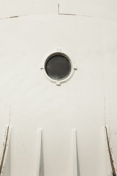 View of the porthole window on the white exterior wall of the historic Saxby Lighthouse in Saxby, Laane maakond, Estonia.