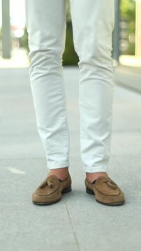 Stylish man in loafers walking on city sidewalk