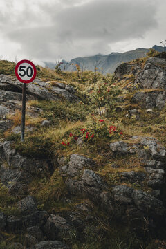 Sund, Norway - 04 September 2025: View of a speed limit sign standing in a rugged, rocky landscape with sparse vegetation and mountains under a cloudy sky in Sund, Nordland, Norway.