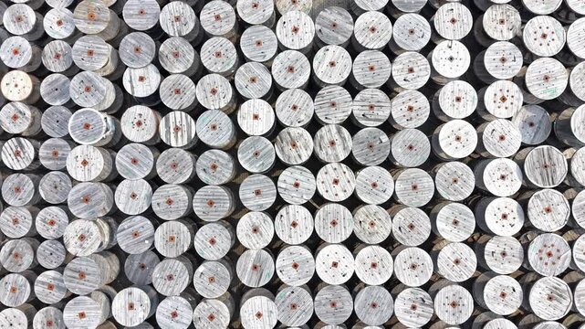 Aerial view of a warehouse displaying a large arrangement of wooden cable reels organized in rows, showcasing a systematic layout across the expansive concrete surface. Industrial place