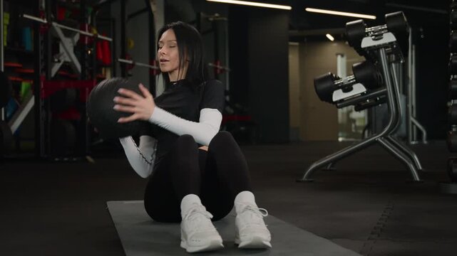 Athletic Caucasian sportswoman doing twist exercise with medicine ball in dark gym fitness club active workout training abs muscles woman athlete female strong body equipment functional movement core
