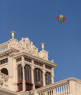 View of a colorful kite flying in the clear blue sky above the ornate, historic architecture of a building in Lahore, Punjab, Pakistan.