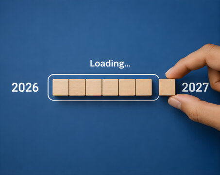 Hand completing a loading bar with a wooden block representing the transition from 2026 to 2027 year