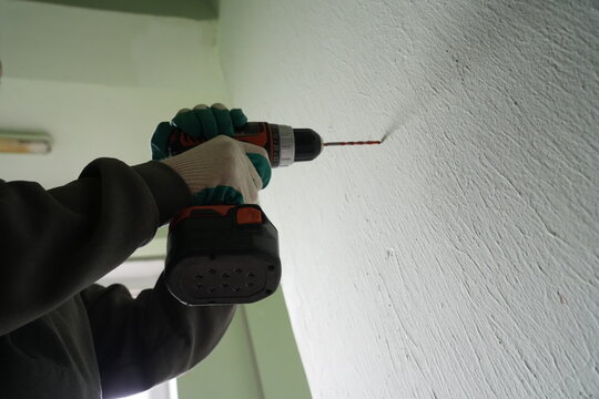 Low angle of worker drilling plaster wall with power tool