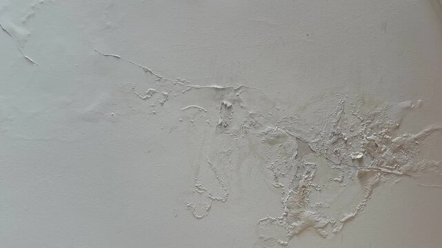 Close up  of a ceiling with peeling paint and plaster from water leak and moisture damage. Home repair, renovation, property inspection, and insurance concept.