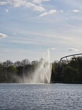 View of the fountain in Maschsee lake with trees and blue sky in the background in Hanover, Lower Saxony, Germany.