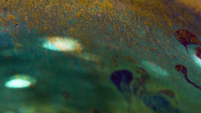 Macro view of vibrant turquoise and gold fluid interference pattern swirling on surface