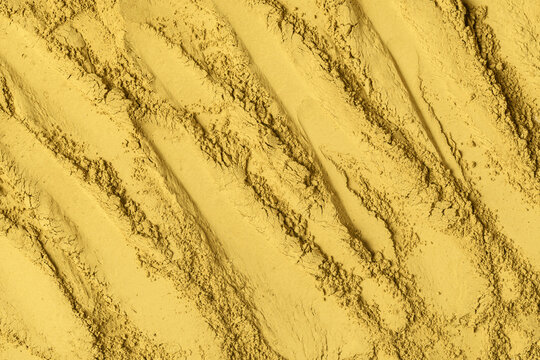 Roasted hojicha powder forms sweeping diagonal ridges across golden surface and provides tactile backdrop for tea and wellness design.