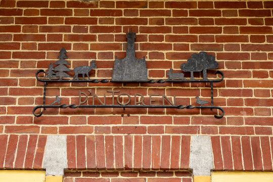 View of the metal sign for De Brandtoren featuring silhouettes of a tower, a deer, and a rabbit mounted on a red brick wall in Esbeek, Noord-Brabant, Netherlands.
