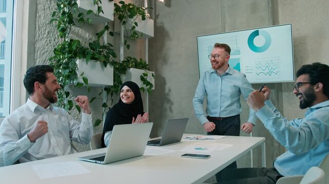 Cheering happy diverse multiethnic business team celebrating success startup indoor office Arabian businessmen muslim businesswoman victory work laptop partners teamwork colleagues win deal boardroom