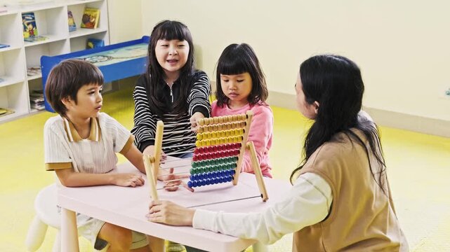 Teacher guides three children using a colorful abacus in a bright preschool classroom