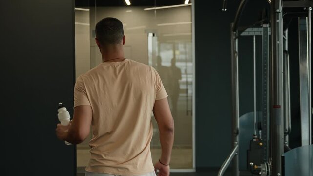 Back view African American man sportsman walking with water bottle in fitness gym athletic male trainer going locker room after workout bodybuilder boxer instructor healthy active lifestyle sport club