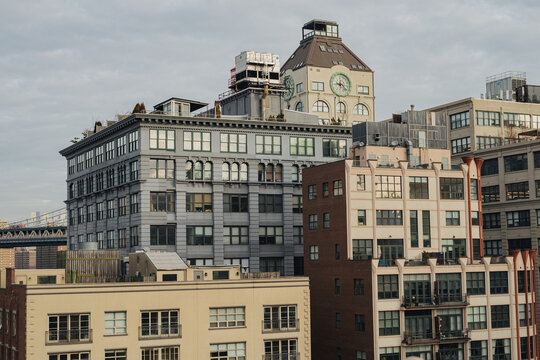 View of the Brooklyn Bridge and surrounding historic industrial buildings with large windows and a clock tower in New York, New York, United States.