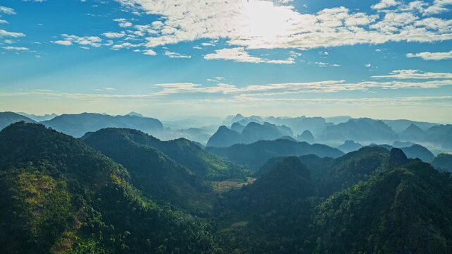 A breathtaking aerial view of a lush green valley surrounded by towering mountains. A winding river cuts through the serene landscape under a clear, expansive sky, creating a sense of natural beauty